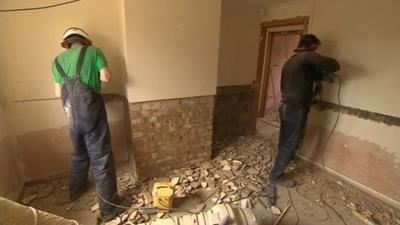 Builders stripping plaster from walls