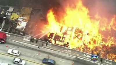 Fire fighters spray water on the blaze from a motorway overpass