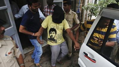 Police officers escort a man (face covered) arrested in connection with the gang rape of a photo journalist in Mumbai