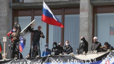 Pro-Russian activists who seized the main administration building in the eastern Ukrainian city of Donetsk deploy a flag of the so-called Donetsk Republic and hold a Russian flag on April 7, 2014, in Donetsk