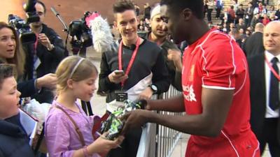 Liverpool defender Kolo Toure hands his football boots to a young fan at the launch of Liverpool's new kit on Thursday.