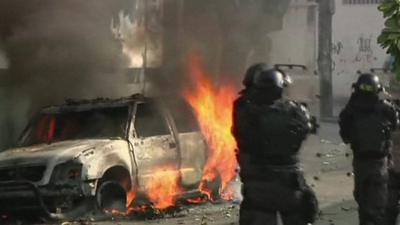 Police officers and burning vehicle