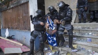 Police officers carry a squatter during an eviction from an abandoned building in Rio de Janeiro, Brazil