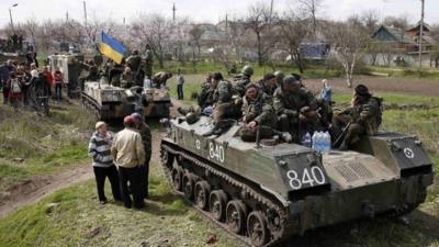 Ukrainian soldiers sit on top of armoured personnel carriers while surrounded by pro-Russia protesters in Kramatorsk