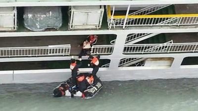 A passenger is rescued by South Korean maritime policemen