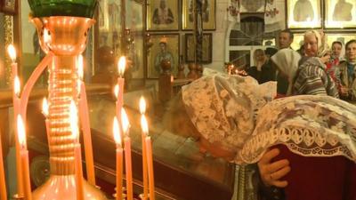 Woman and candles at Orthodox church in Ukraine