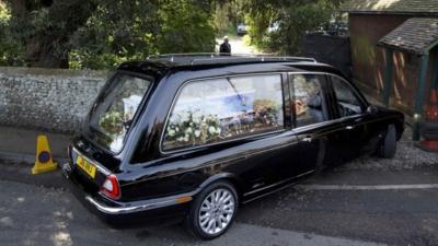 A hearse carrying the coffin of Peaches Geldof, painted with a picture of her family, arrives at church