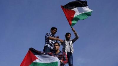 Palestinians hold national flags as they celebrate the reconciliation agreement in Gaza City - 23 April 2014