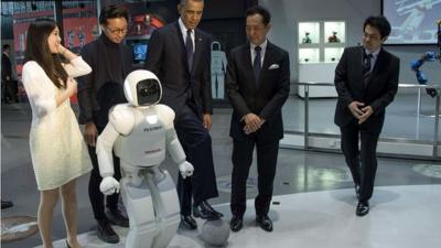 President Obama positions a football next to robot