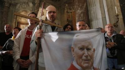 Polish pilgrims hold a flag portraying Pope John Paul II during a vigil prayer