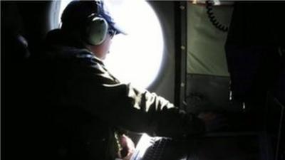 A man looks for wreckage through the window of a search plane