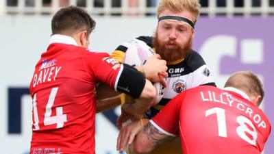 Castleford Tigers’ Oliver Holmes is tackled by Sheffield Eagles’ James Davey and Tom Lillycrop