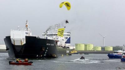 A member of Greenpeace in a hang-glider, carrying a banner over the Russian oil tanker