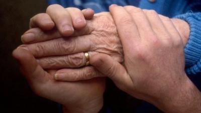 Health carer holding the hand of an elderly patient.