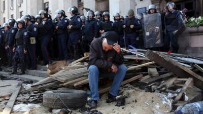 A Pro-Russian activist sits in front of policemen guarding the burned trade union building in the southern Ukrainian city of Odessa