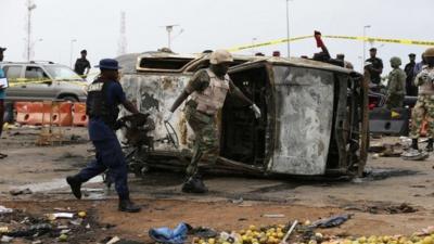 Two men move part of a damaged car at the scene of a car bomb attack in Abuja, May 2, 2014.