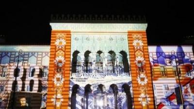 3D mapping projections of the logo of the 1982 Sarajevo Winter Olympics are seen on the facade of the City Hall