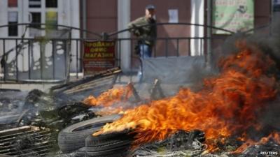 Man walks past burning barricade