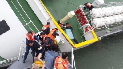 This screen grab taken from a video released by Korea Coast Guard on April 28, 2014 shows the sunken South Korean ferry "Sewol" captain Lee Joon-Seok (L), wearing a sweater and underpants, being rescued from the tilting vessel