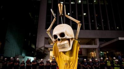 Demonstrator wearing skull and Brazilian football strip