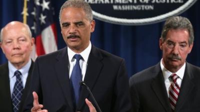 U.S. Attorney General Eric Holder (C) speaks as Deputy Attorney General James Cole (R) and IRS Commissioner John Koskinen (L) listen during a news conference