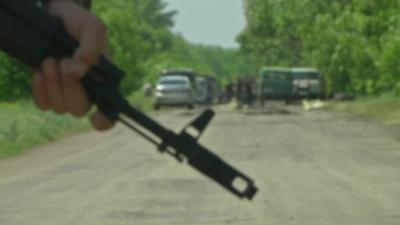 Man holds gun near vehicles on road in Ukraine