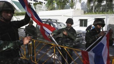 Thai soldiers hold national flags as they dismantle an anti-government encampment in central Bangkok