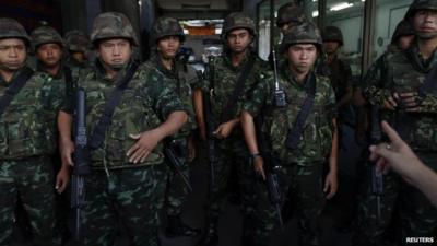 A man gestures towards soldiers who arrived to control a protest against military rule in central Bangkok