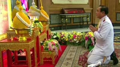 General Prayut Chan-O-Cha paying respects in front of a portrait of Thai King Bhumibol Adulyadej