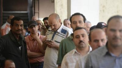 Egyptian voters await their turn in a queue outside a polling station in the Gamaliya suburb of Cairo