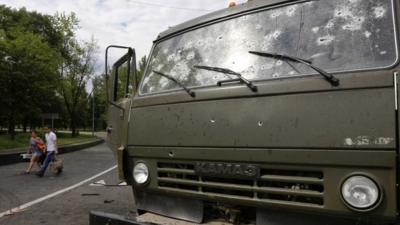 A couple walks past a wrecked Kamaz truck as they flee an area near the Donetsk airport