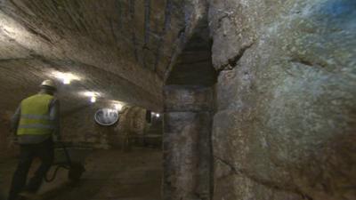 Workman pushing wheelbarrow in Bradford's underground tunnel