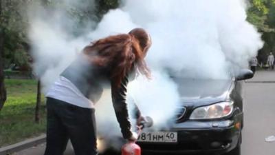 Woman sprays fire extinguisher at car