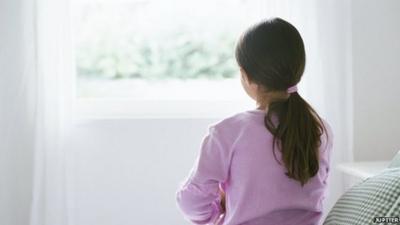 A young girl sat on a bed