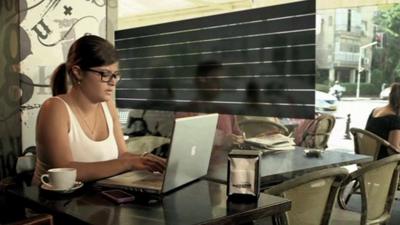 A woman in a coffee shop using a smart glass privacy screen