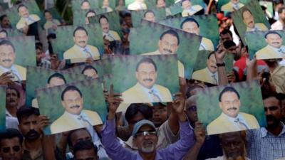 Supporters of Pakistan's MQM party hold photographs of their party leader Altaf Hussain