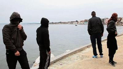 Men with covered faces standing by bay