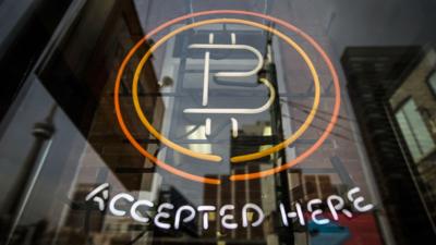 A sign reads "Bitcoin accepted here"