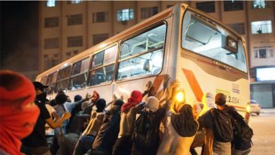 Brazilian protesters pushing over a bus