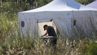 A British police officer sifts through soil under a white tent, after it was removed from a site of an area of wasteland during a search for evidence of Madeleine McCann in the town of Praia da Luz, Portugal