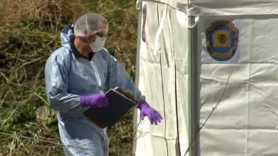 Forensic officer outside white tent