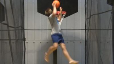 A boy playing basket ball on a trampoline at the Camberley park