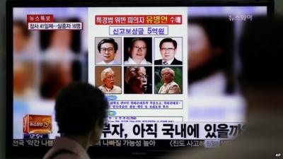 A woman watches a TV news program showing the reward poster of Yoo Byung-eun