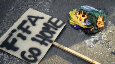 'Fifa go home' sign next to burning Brazilian flag