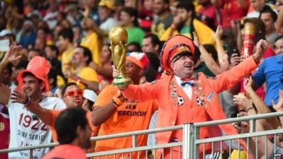 Netherlands fan dressed in orange with fake World Cup trophy