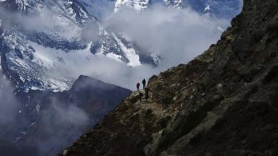 Trekkers walk in front of Mount Thamserku while on their way back from Everest base camp at Pheriche