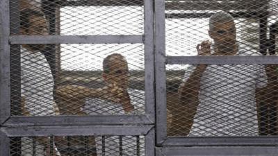 Baher Mohamed (left), Peter Greste (centre) and Mohamed Fahmy behind bars in a court in Cairo, 1 June 2014