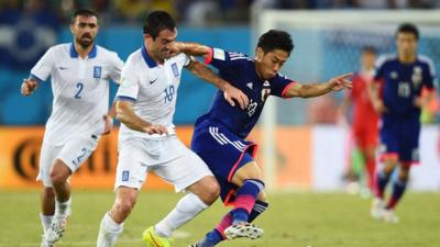 Greece's Georgios Karagounis battles with Japan's Shinji Kagawa