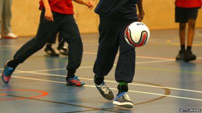 Children playing football in a school gym