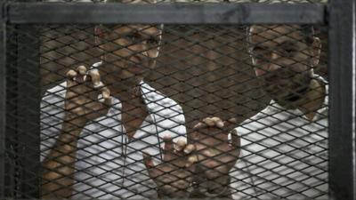 Al-Jazeera channel's Australian journalist Peter Greste (left) and Egyptian journalist Baher Mohamed stand inside the defendants' cage during their trial near Cairo's Tora prison, 1 June 2014